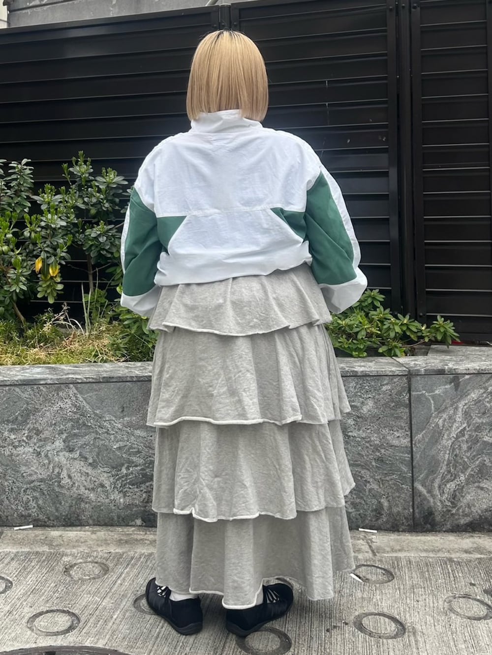 グレー系のスカート、ホワイト系のナイロンジャケットを着用したレディースの春コーディネートの4枚目の写真