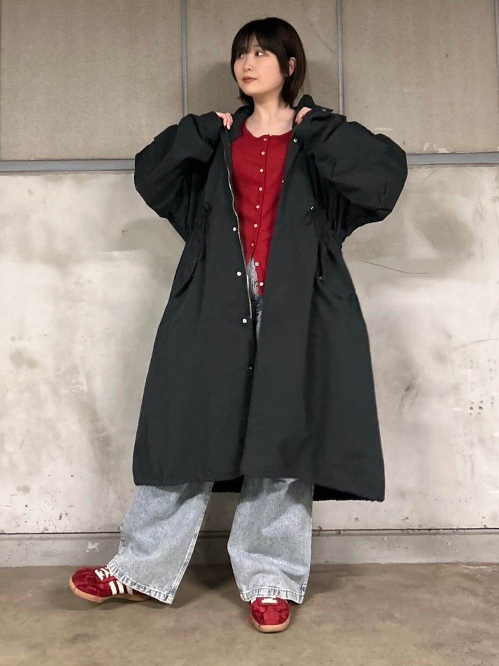 ブラック系のモッズコート、ブルー系のデニムパンツ、レッド系のカーディガン/ボレロを着用したレディースの春コーディネートの3枚目の写真