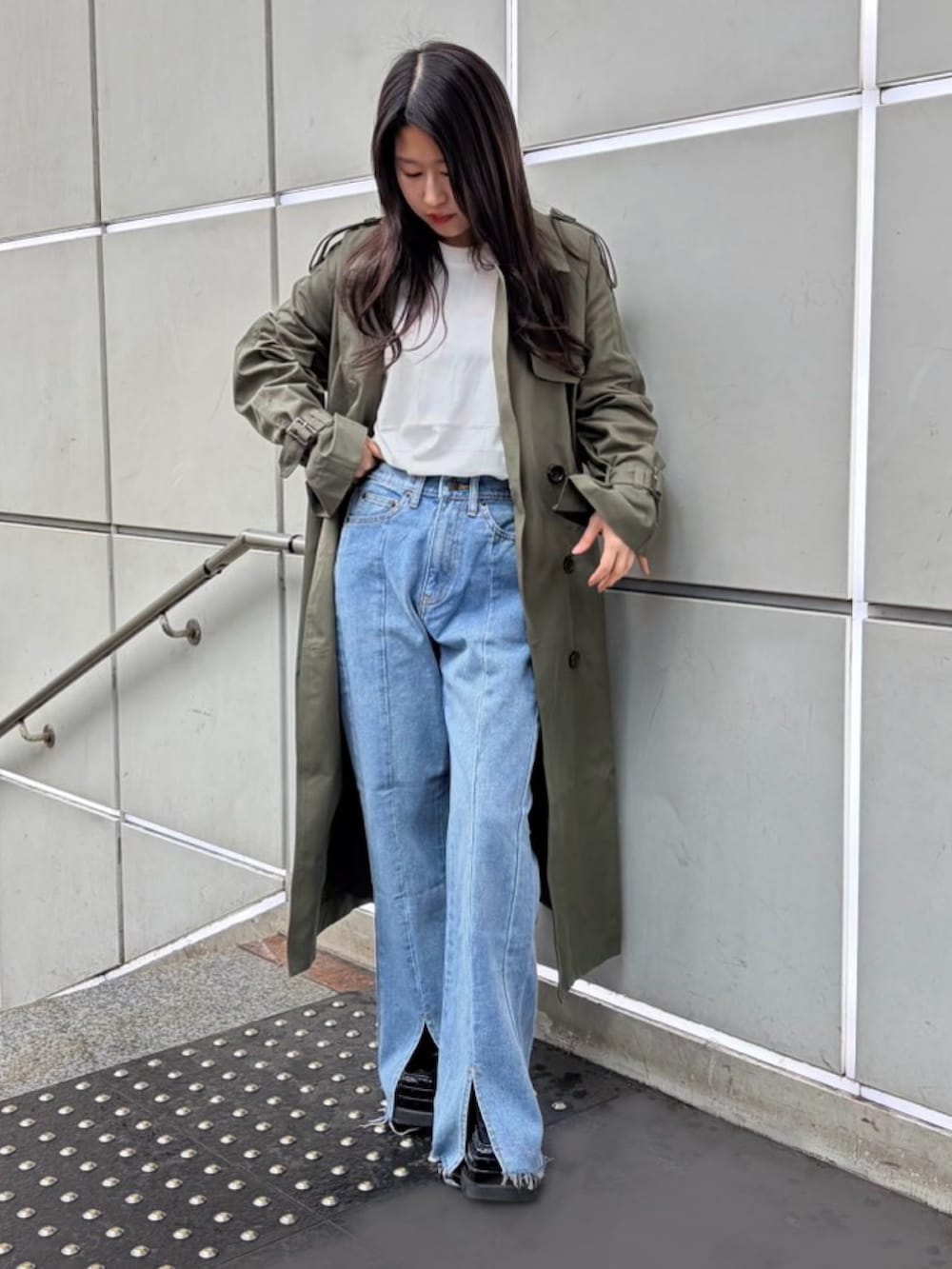 グリーン系のトレンチコート、ブルー系のデニムパンツ、ホワイト系のTシャツ/カットソーを着用したレディースの春コーディネートの2枚目の写真