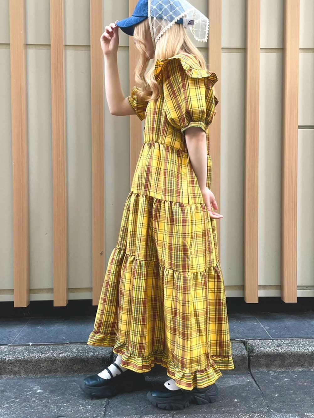 イエロー系のワンピース、ブルー系のキャップを着用したレディースの夏コーディネートの3枚目の写真