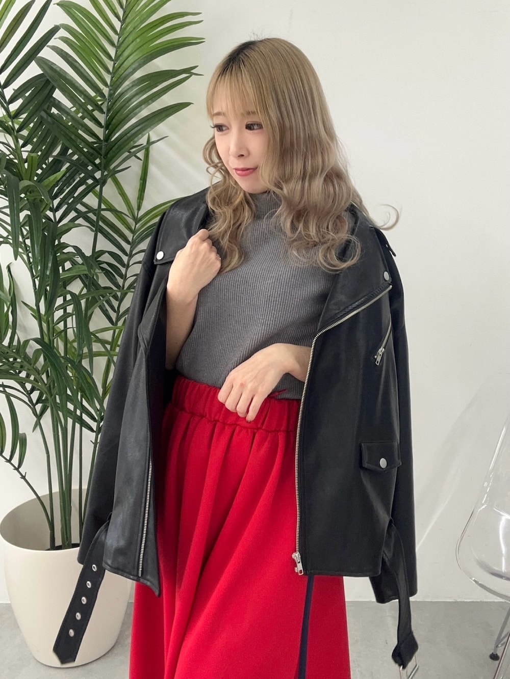 レッド系のスカート、ブラック系のライダースジャケット、ブラック系のトップスを着用したレディースの冬コーディネートの2枚目の写真