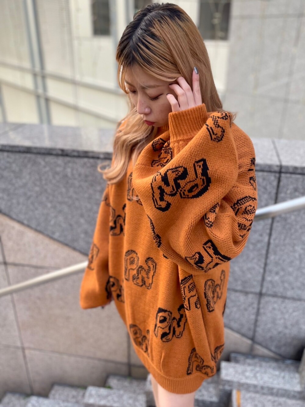 オレンジ系のニット/セーター、ブラック系のブーツ、ブラック系のTシャツ/カットソーを着用したレディースの冬コーディネートの2枚目の写真