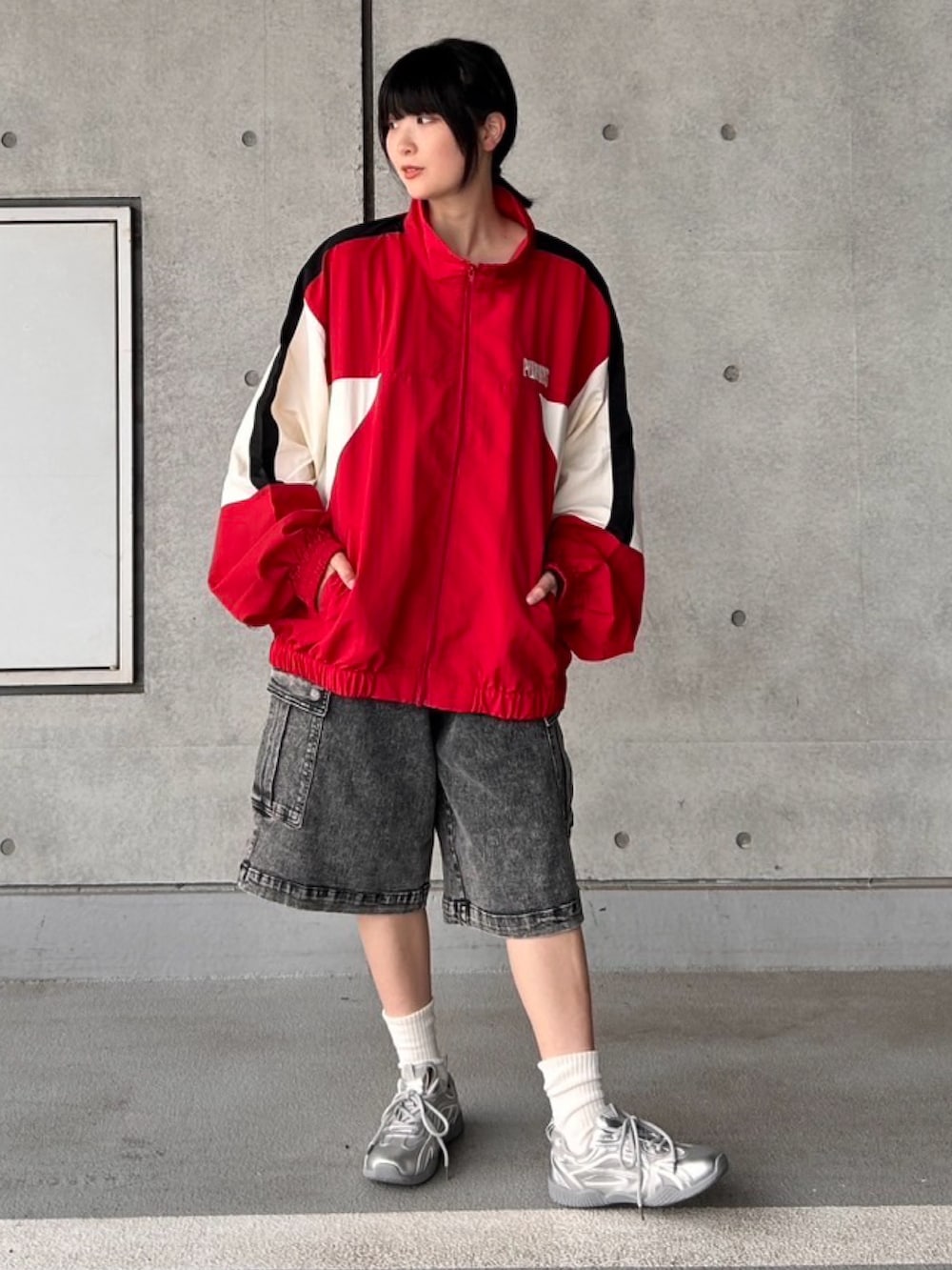 レッド系のナイロンジャケット、ブラック系のデニムパンツを着用したレディースの秋コーディネートの2枚目の写真