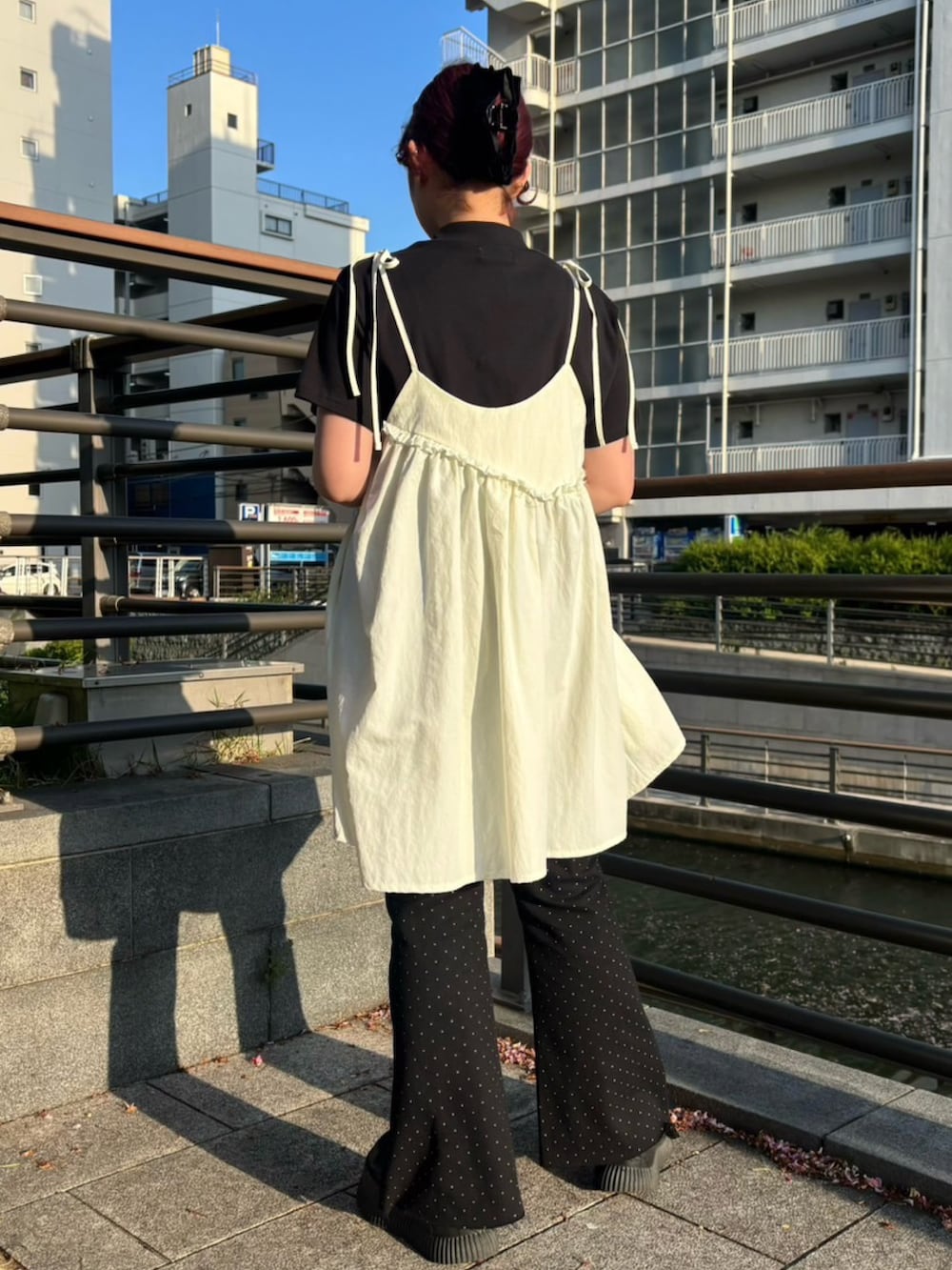 ブラック系のデニムパンツ、ホワイト系のワンピース、ブラック系のTシャツ/カットソーを着用したレディースの春コーディネートの4枚目の写真
