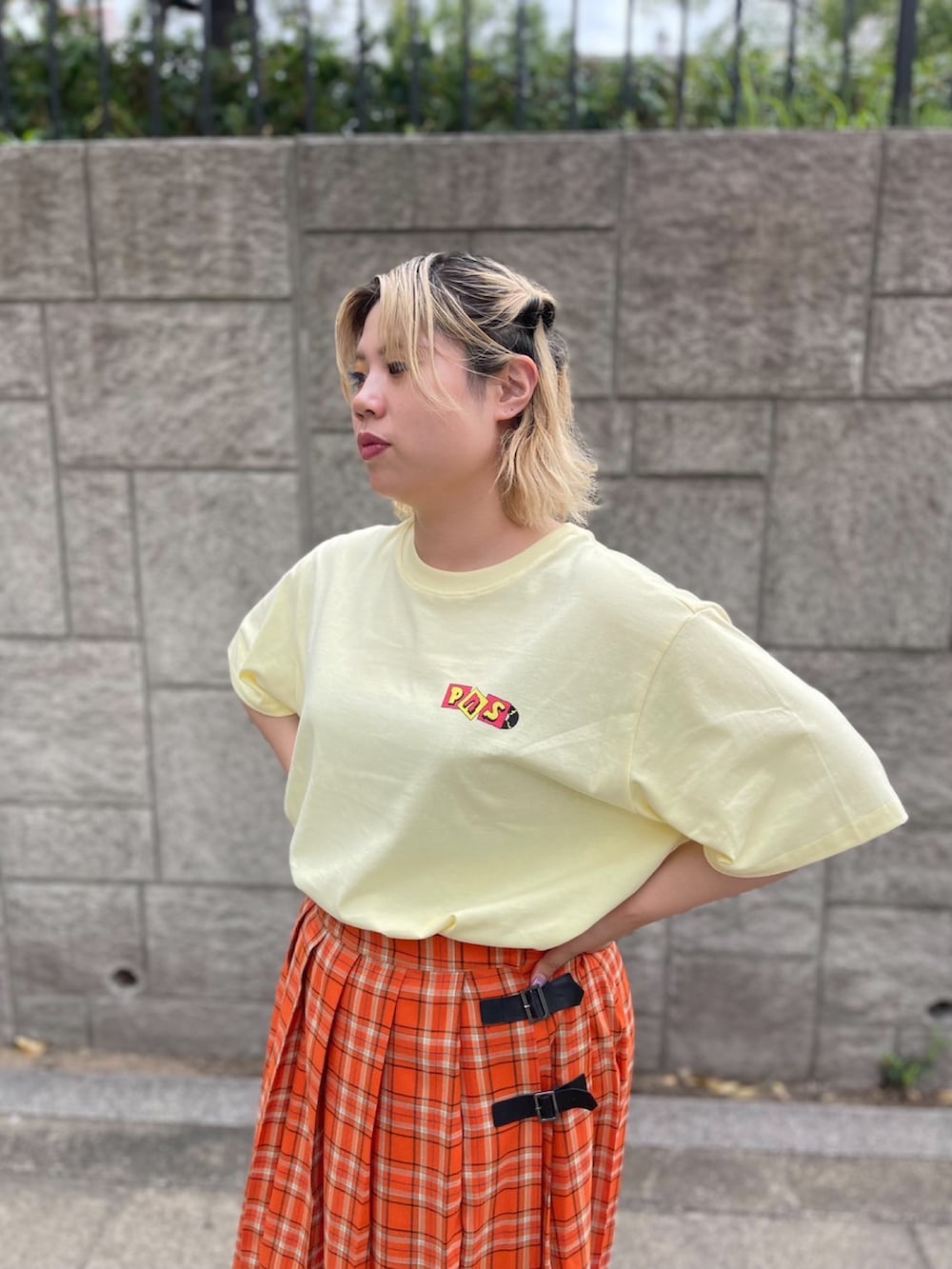 オレンジ系のスカート、イエロー系のTシャツ/カットソーを着用したレディースの夏コーディネートの3枚目の写真