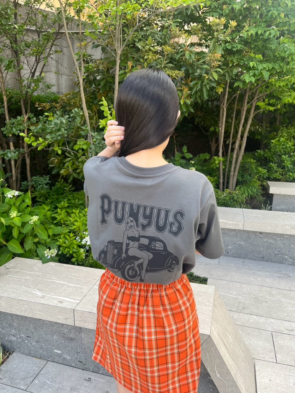 オレンジ系のスカート、ブラック系のTシャツ/カットソーを着用したレディースの春コーディネートの5枚目の写真