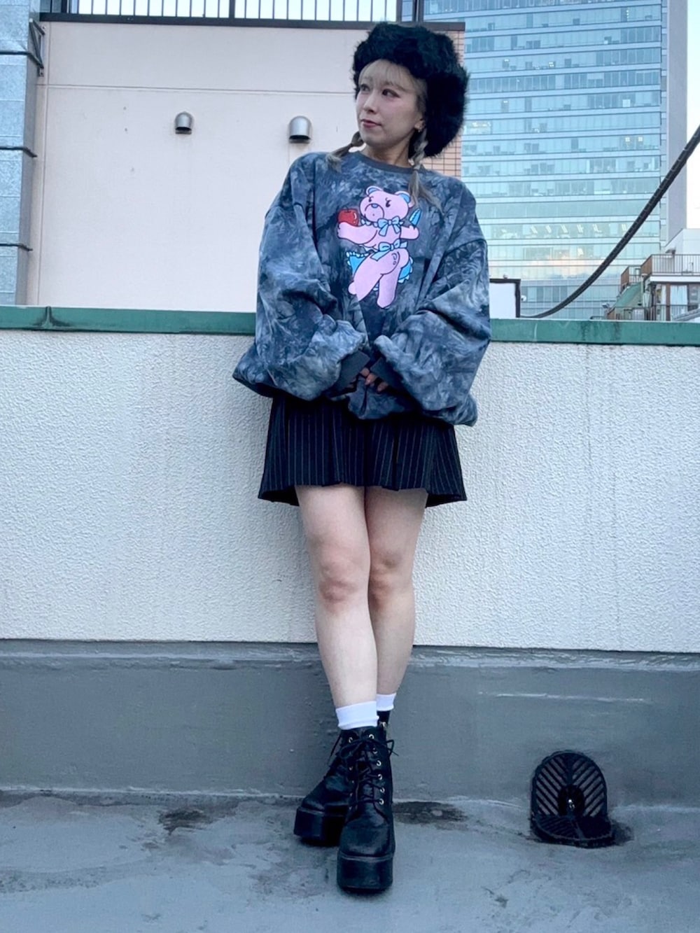 ブラック系のスウェット、ブラック系のスカート、ブラック系のキャップを着用したレディースの冬コーディネートの2枚目の写真