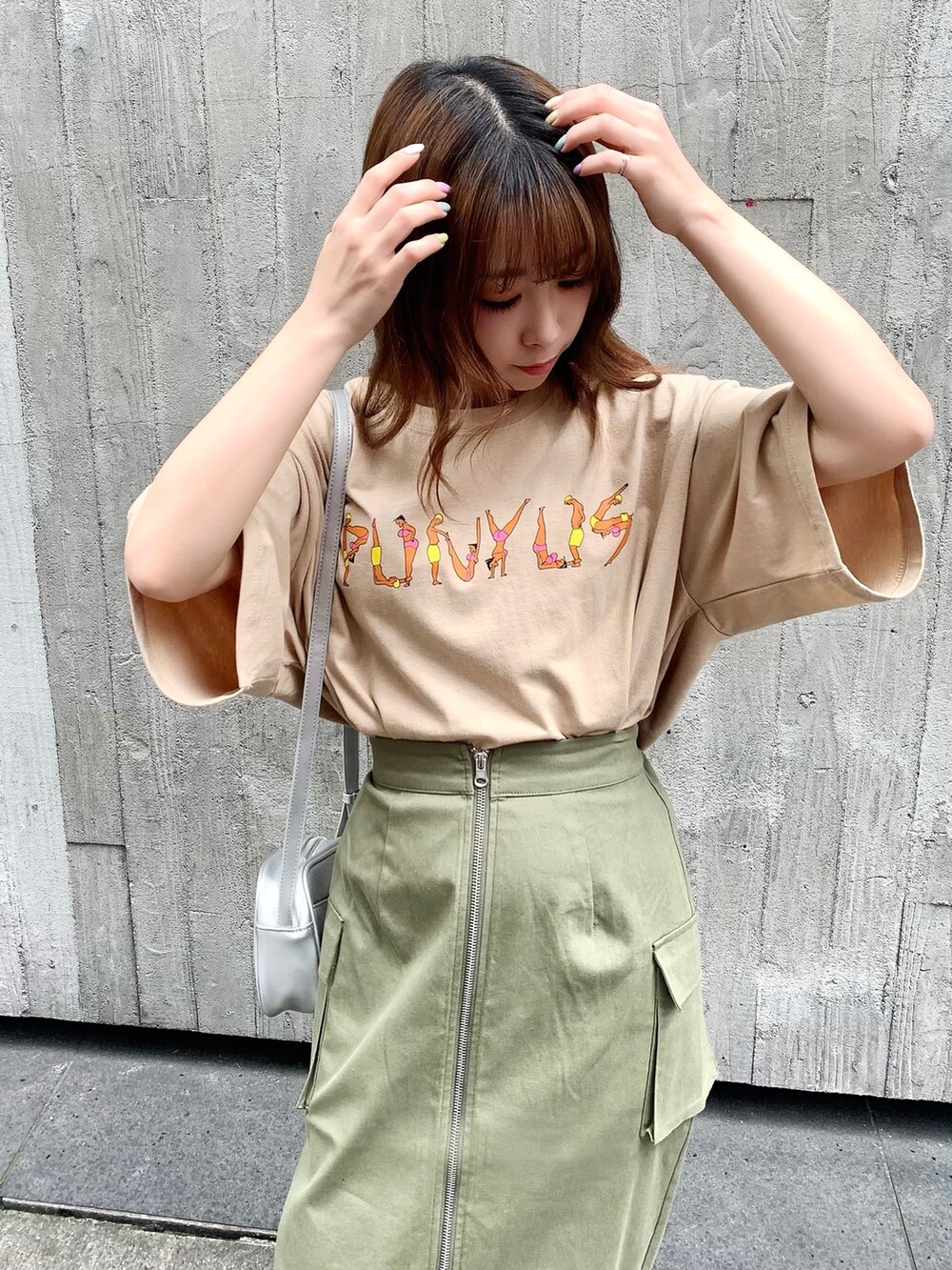 グリーン系のスカート、ベージュ系のTシャツ/カットソー、シルバー系のショルダーバッグを着用したレディースの夏コーディネートの2枚目の写真