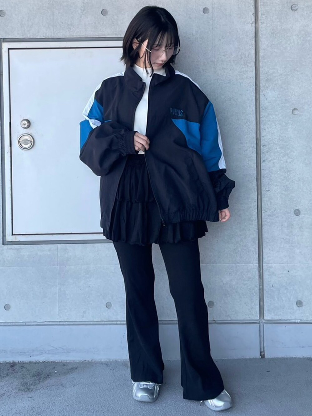 ブラック系のその他パンツ、ブラック系のナイロンジャケット、ホワイト系のTシャツ/カットソーを着用したレディースの春コーディネートの2枚目の写真