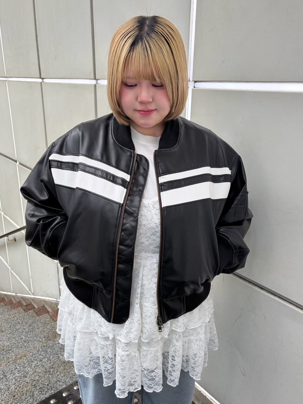 ブルー系のデニムパンツ、ホワイト系のワンピース、ブラック系のブルゾンを着用したレディースの春コーディネートの3枚目の写真