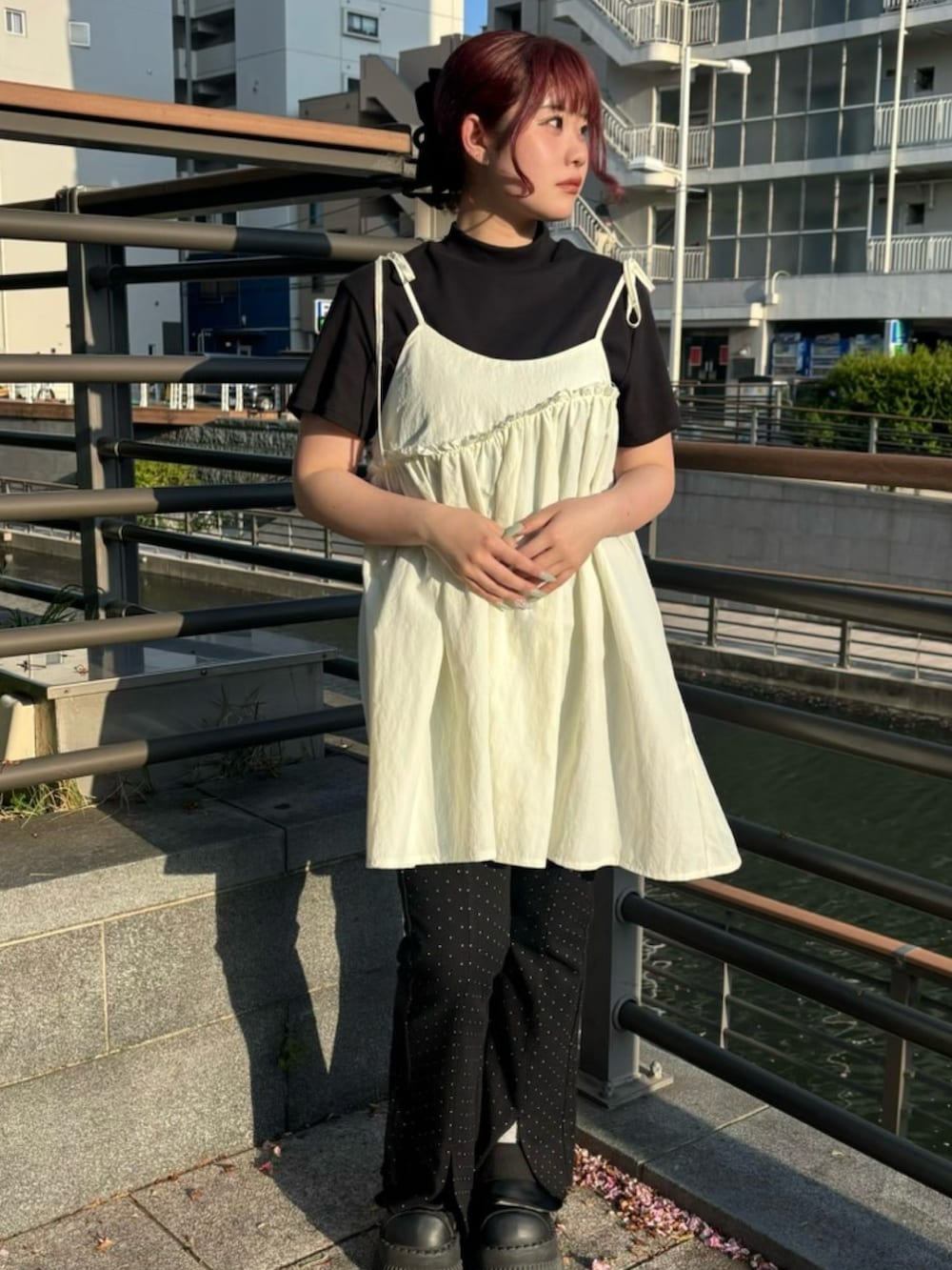 ブラック系のデニムパンツ、ホワイト系のワンピース、ブラック系のTシャツ/カットソーを着用したレディースの春コーディネートの2枚目の写真