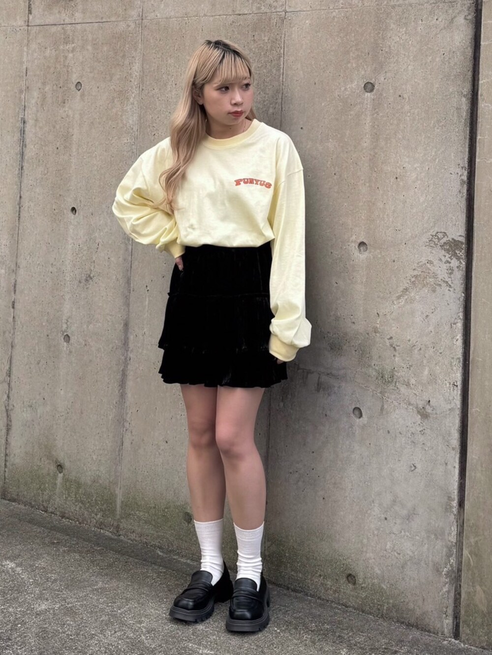 イエロー系のTシャツ/カットソー、ブラック系のスカートを着用したレディースの冬コーディネートの2枚目の写真