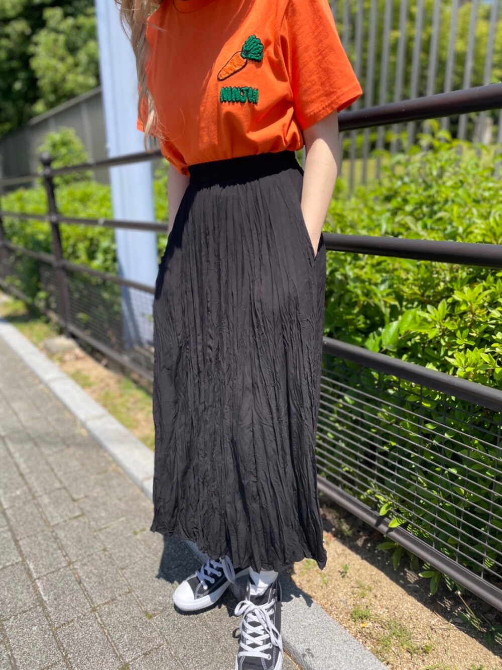 ブラック系のスカート、オレンジ系のTシャツ/カットソーを着用したレディースの春コーディネートの2枚目の写真