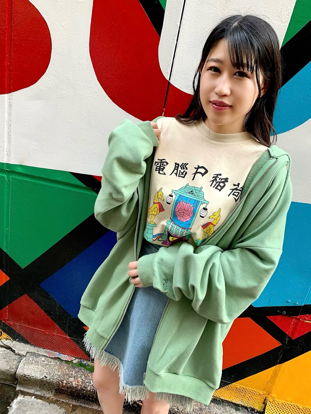 ベージュ系のTシャツ/カットソー、グリーン系のパーカー、ブルー系のデニムスカートを着用したレディースの春コーディネートの3枚目の写真