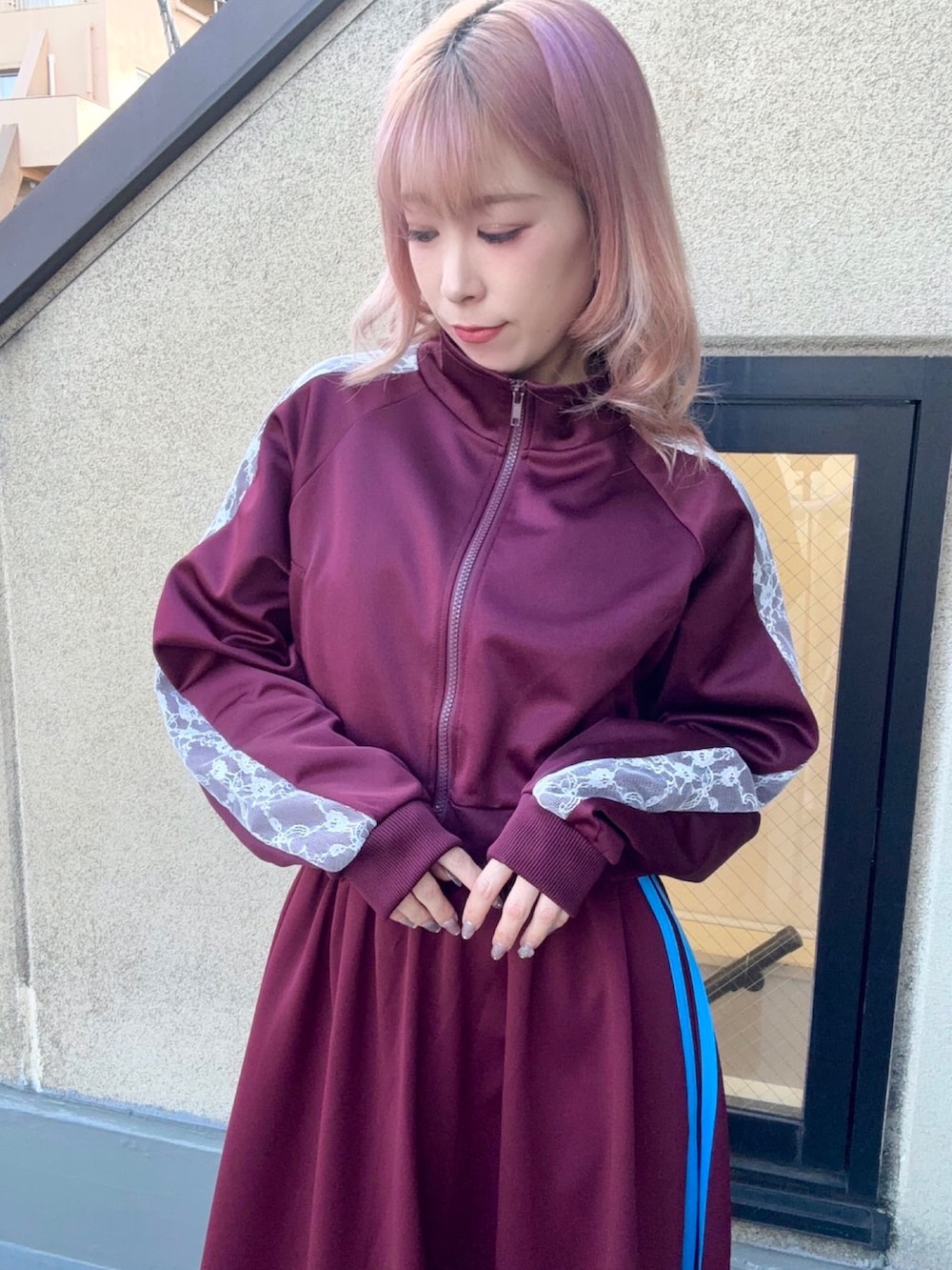 レッド系のジャージ、レッド系のスカートを着用したレディースの秋コーディネートの3枚目の写真