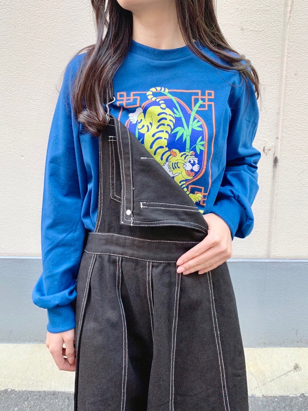 ブラック系のジャンパースカート、ブルー系のTシャツ/カットソーを着用したレディースの秋コーディネートの3枚目の写真