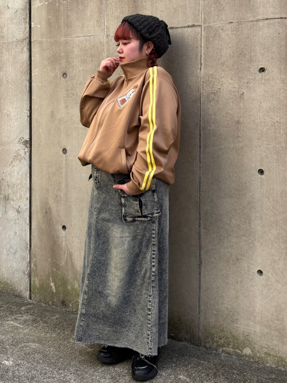 ブラウン系のジャージ、ブルー系のデニムスカート、ブラック系のキャップを着用したレディースの冬コーディネートの2枚目の写真