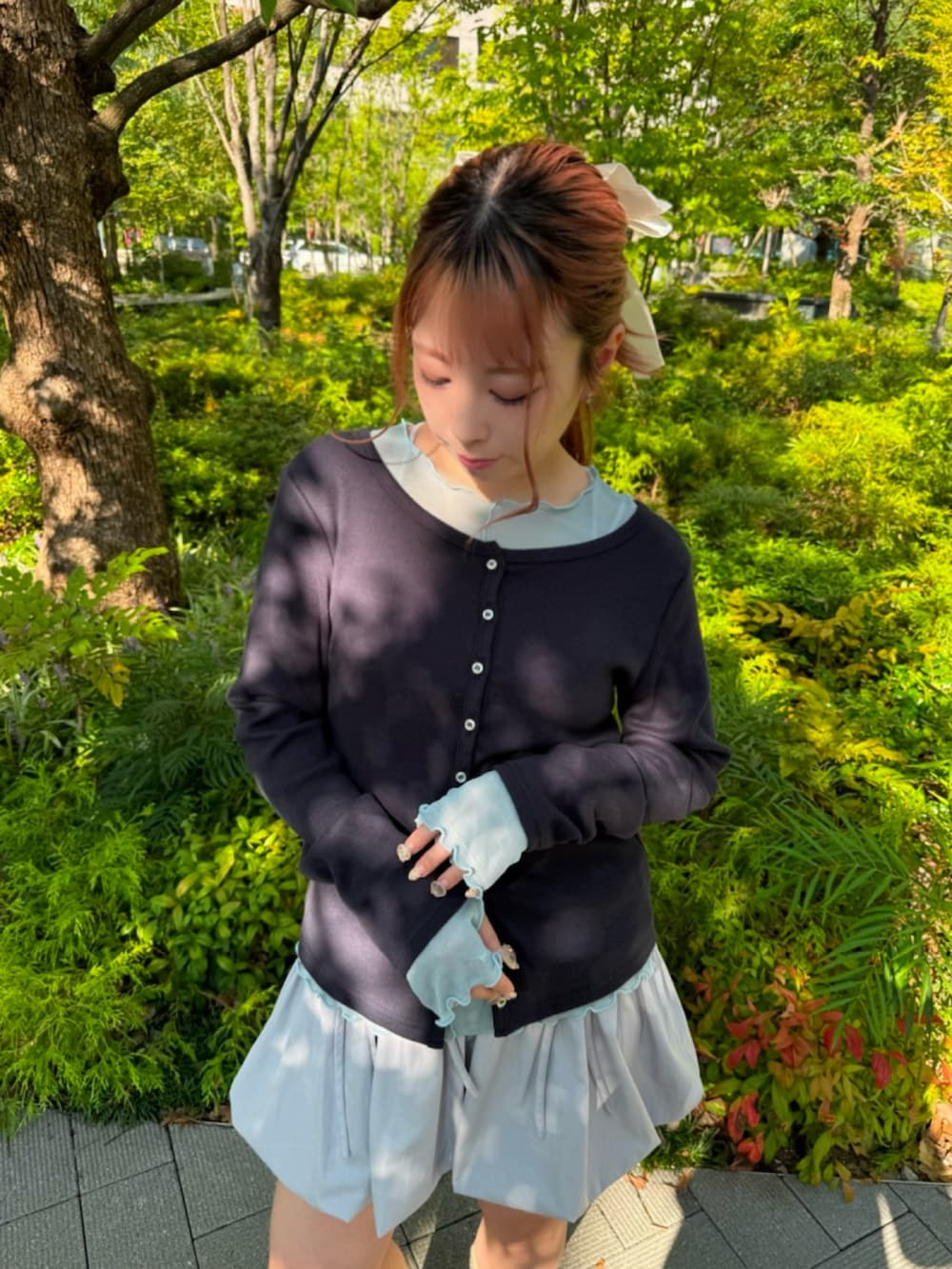 グレー系のスカート、ブルー系のTシャツ/カットソー、ブルー系のカーディガン/ボレロを着用したレディースの秋コーディネートの5枚目の写真