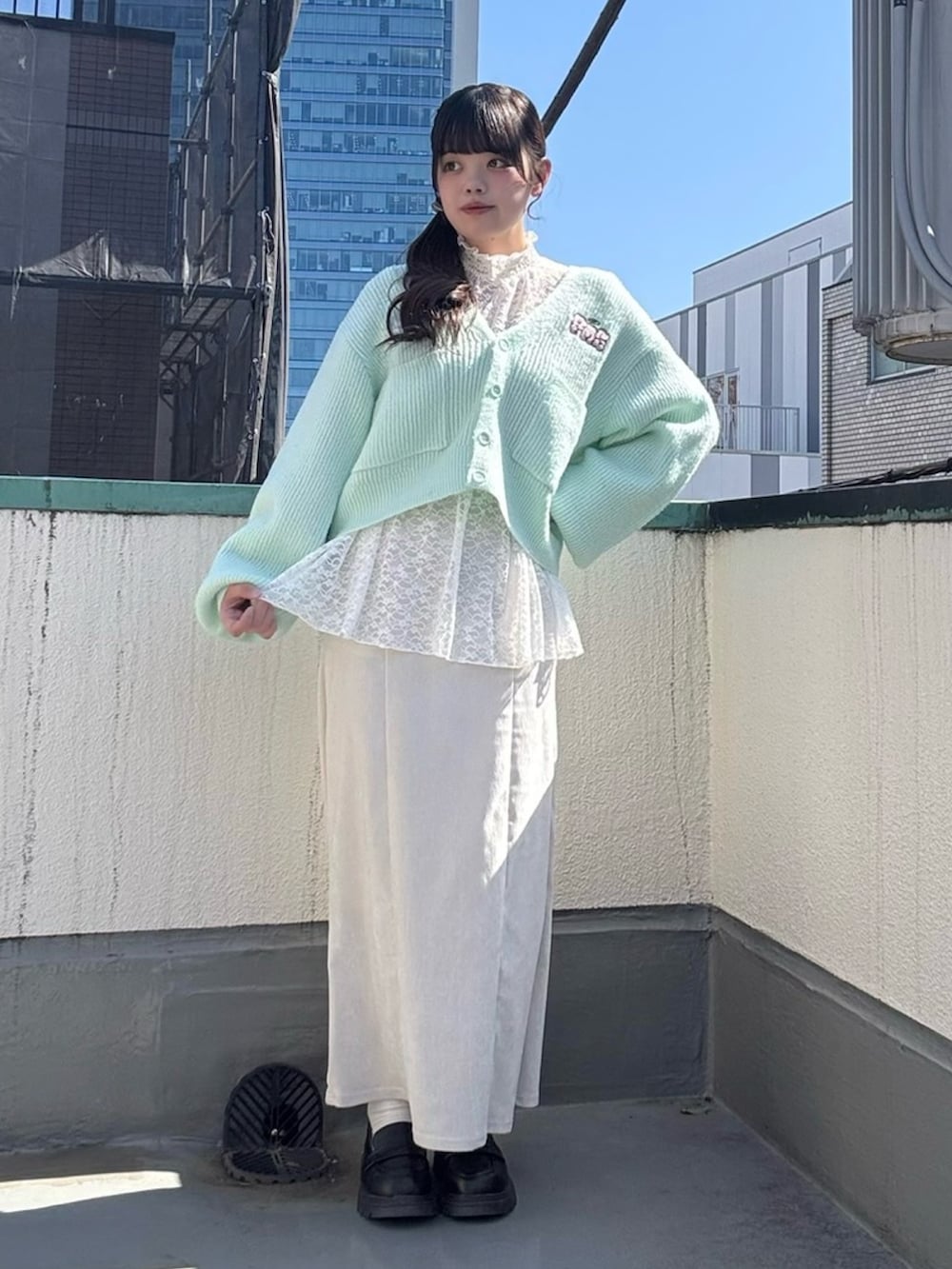 ホワイト系のスカート、ホワイト系のTシャツ/カットソー、グリーン系のカーディガン/ボレロを着用したレディースの春コーディネートの6枚目の写真