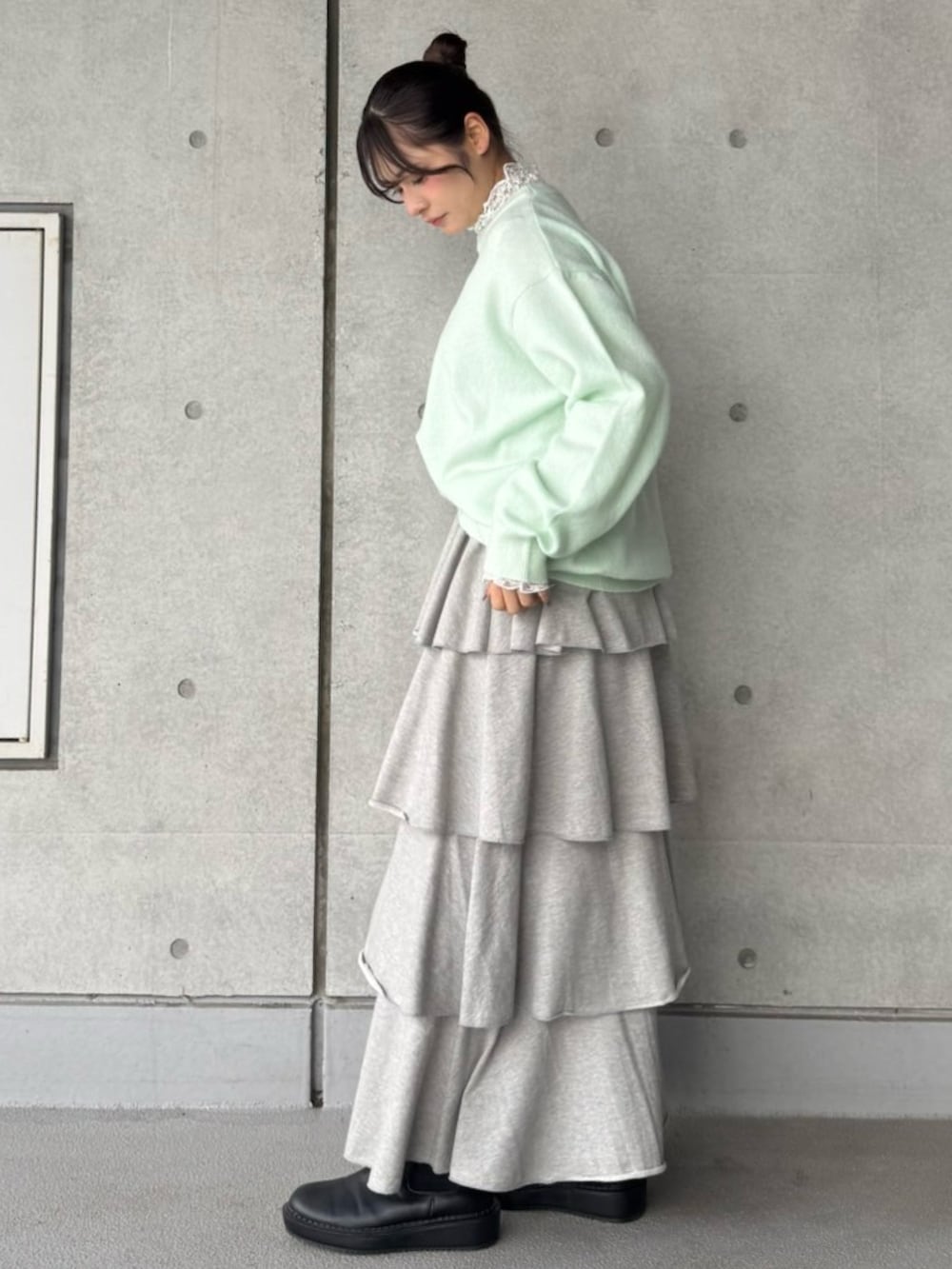 グレー系のスカート、グリーン系のニット/セーター、ホワイト系のTシャツ/カットソーを着用したレディースの冬コーディネートの3枚目の写真