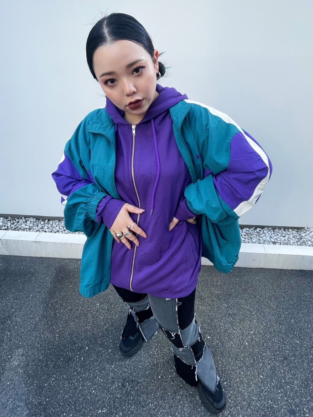 グリーン系のナイロンジャケット、パープル系のパーカー、ブラック系のデニムパンツを着用したレディースの秋コーディネートの2枚目の写真