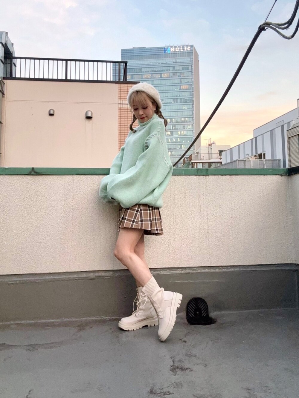 グリーン系のニット/セーター、ベージュ系のスカート、ホワイト系のハンチング/ベレー帽を着用したレディースの冬コーディネートの2枚目の写真