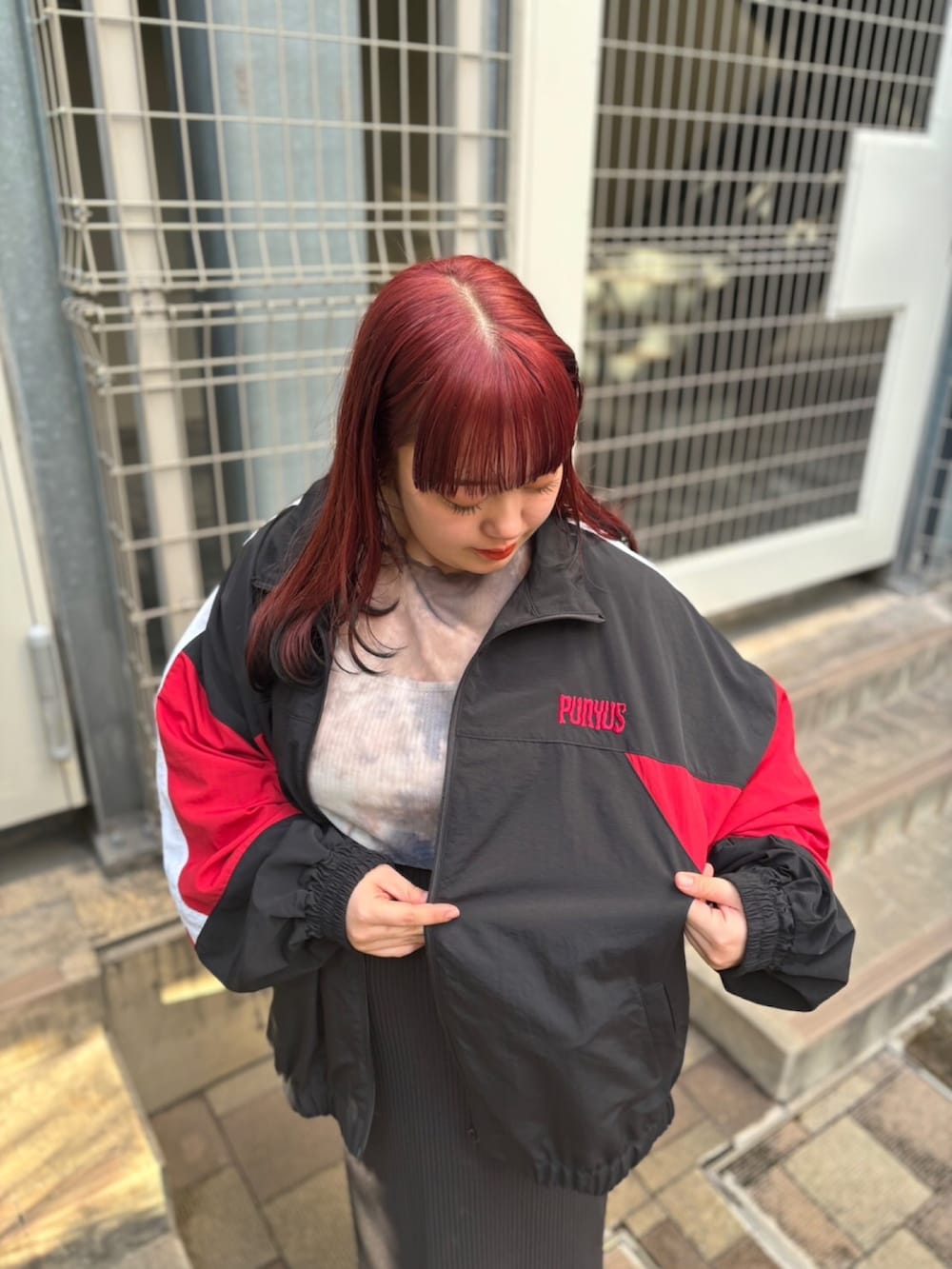 ブラック系のスカート、ブラック系のナイロンジャケット、ブラウン系のTシャツ/カットソーを着用したレディースの秋コーディネートの2枚目の写真