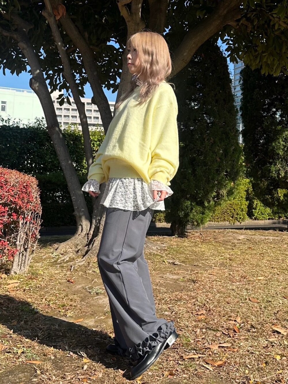 グレー系のスラックス、ホワイト系のTシャツ/カットソー、イエロー系のニット/セーターを着用したレディースの秋コーディネートの2枚目の写真