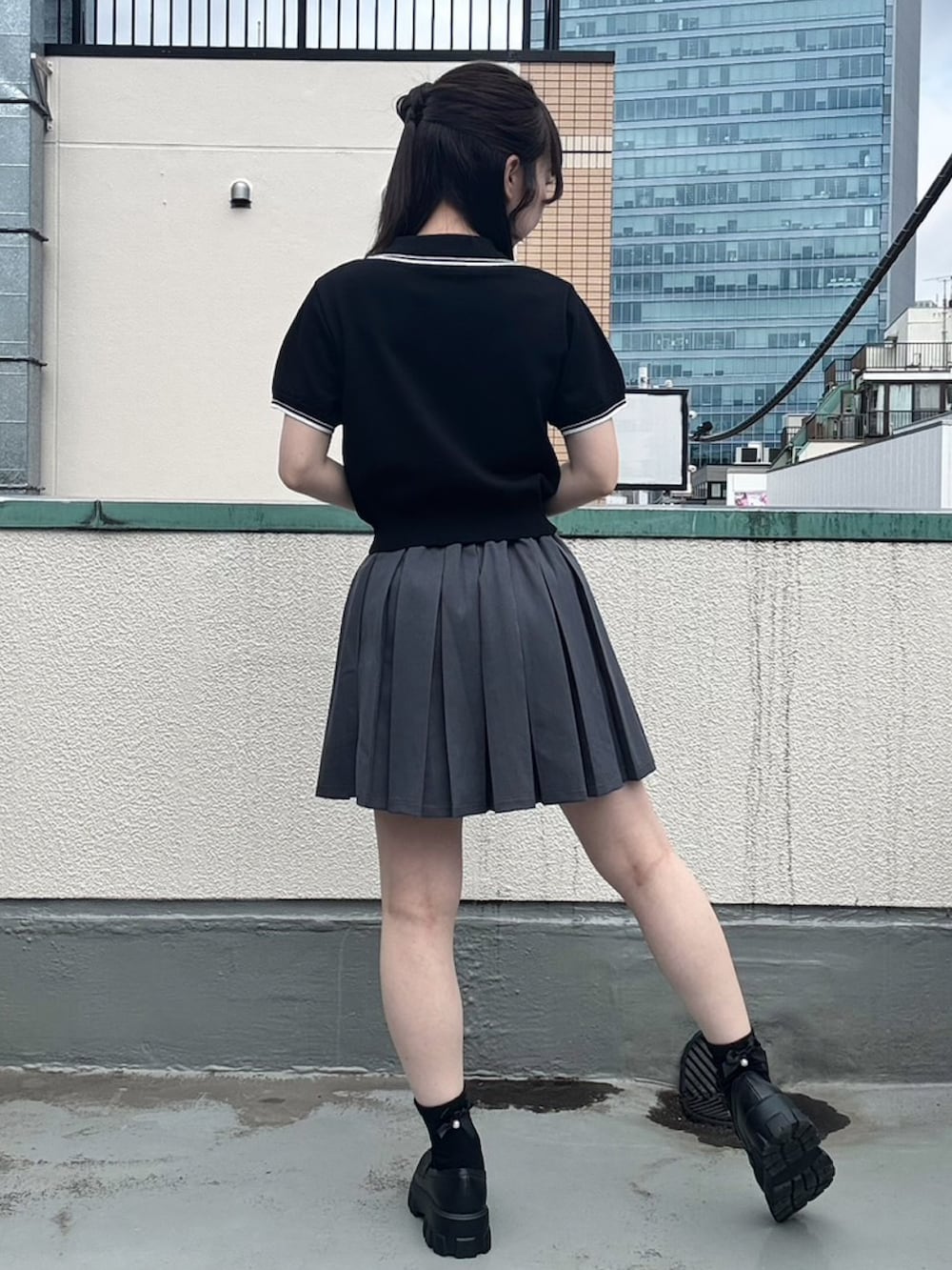 グレー系のスカート、ブラック系のポロシャツを着用したレディースの夏コーディネートの4枚目の写真