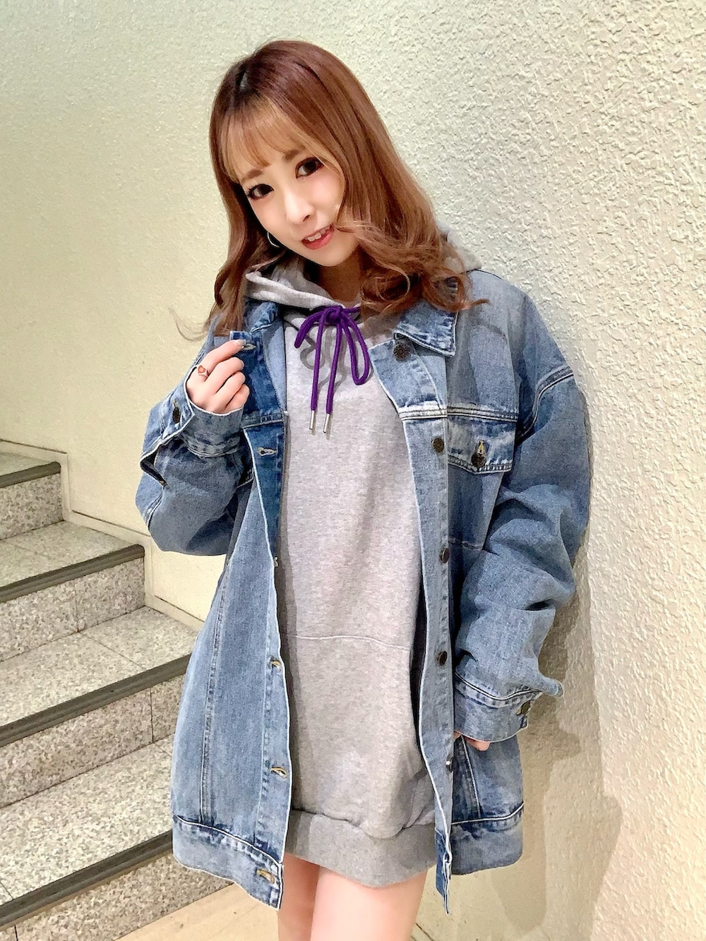 グレー系のパーカー、ブルー系のデニムジャケット、ブラック系のブーツを着用したレディースの冬コーディネートの3枚目の写真