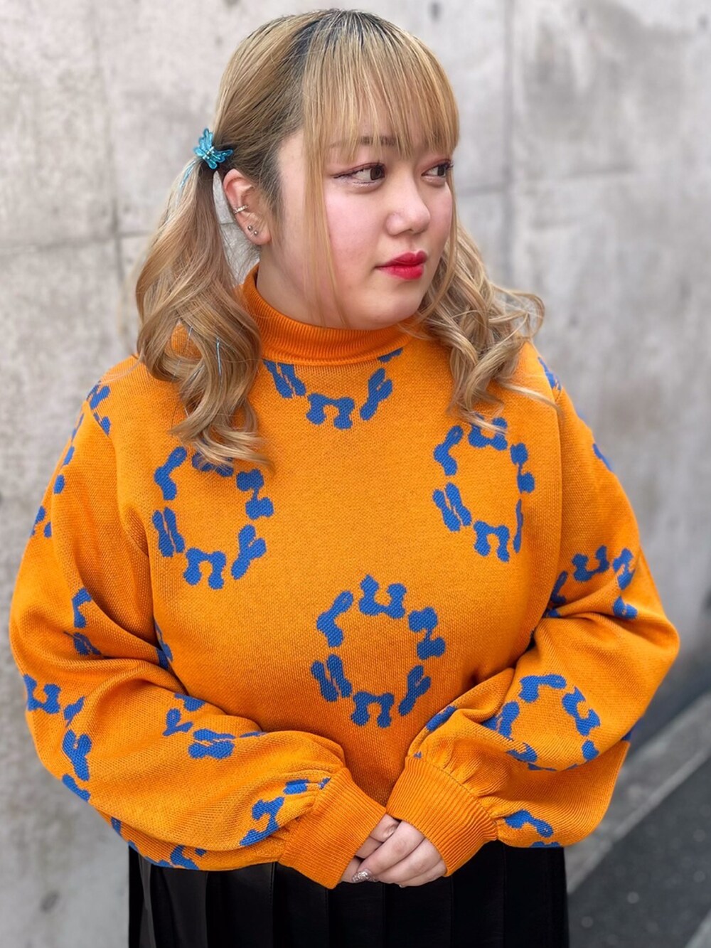 ブラック系のスカート、オレンジ系のニット/セーター、ブラック系のブーツを着用したレディースの冬コーディネートの2枚目の写真