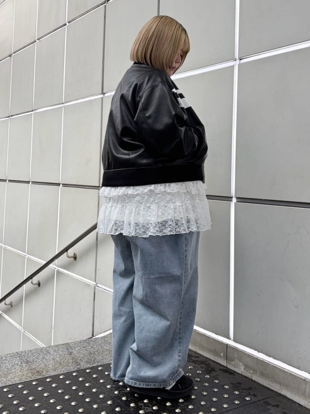 ブルー系のデニムパンツ、ホワイト系のワンピース、ブラック系のブルゾンを着用したレディースの春コーディネートの2枚目の写真