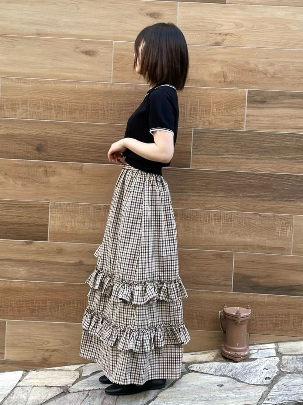 ベージュ系のスカート、ブラック系のポロシャツを着用したレディースの夏コーディネートの4枚目の写真
