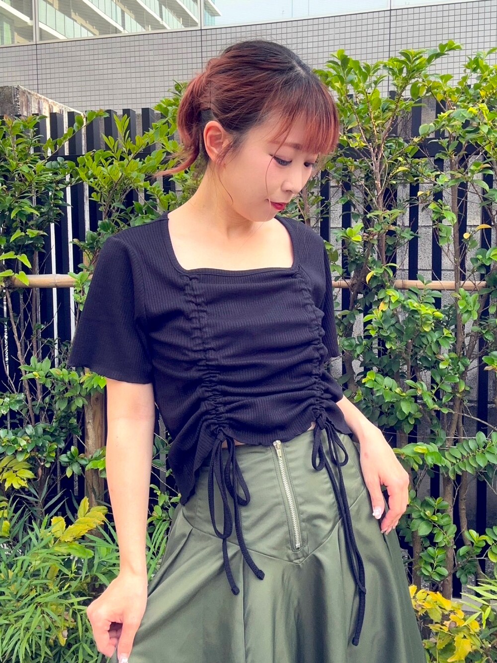 グリーン系のスカート、ブラック系のTシャツ/カットソーを着用したレディースの夏コーディネートの3枚目の写真