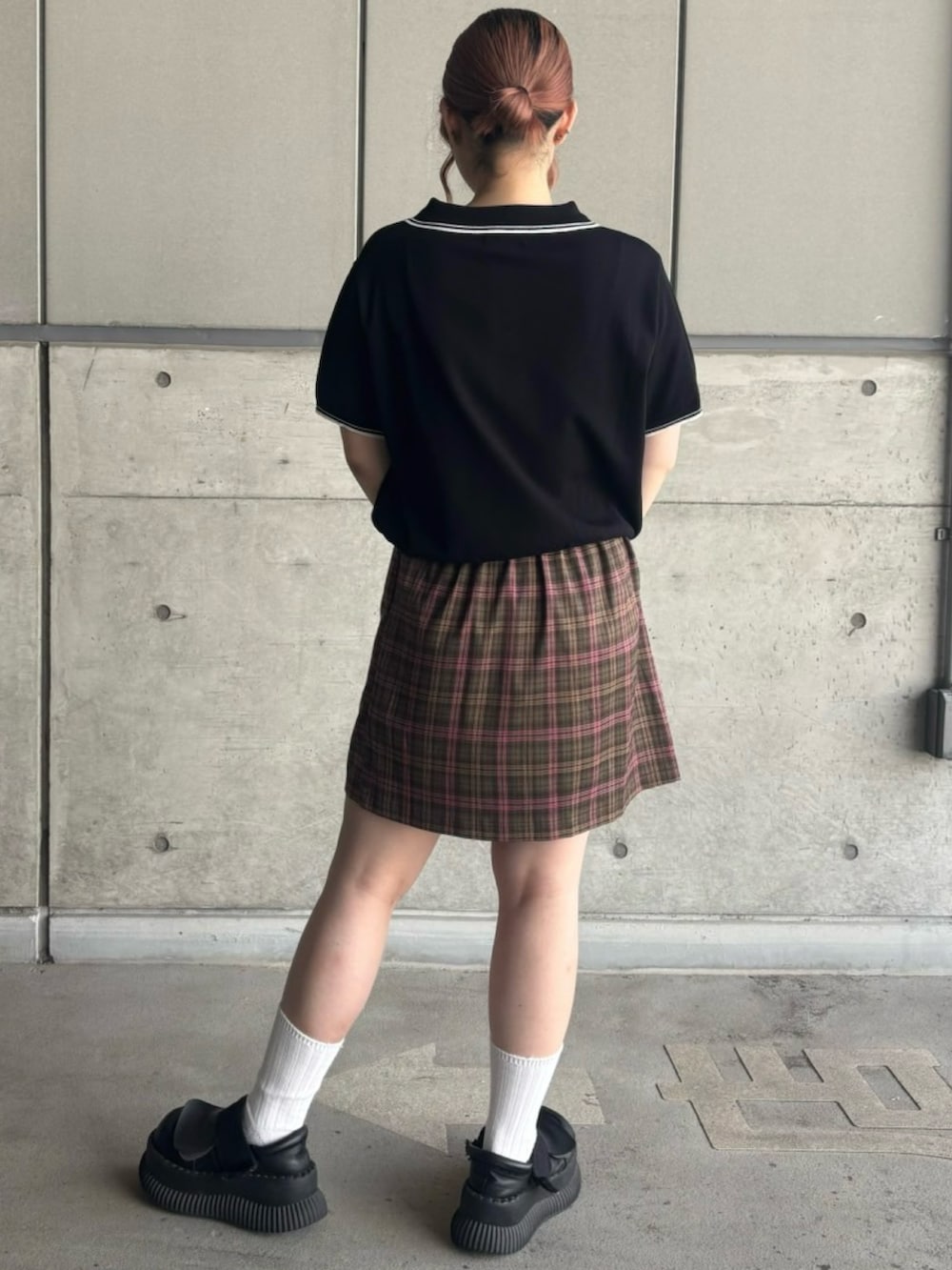グリーン系のスカート、ブラック系のポロシャツを着用したレディースの夏コーディネートの5枚目の写真