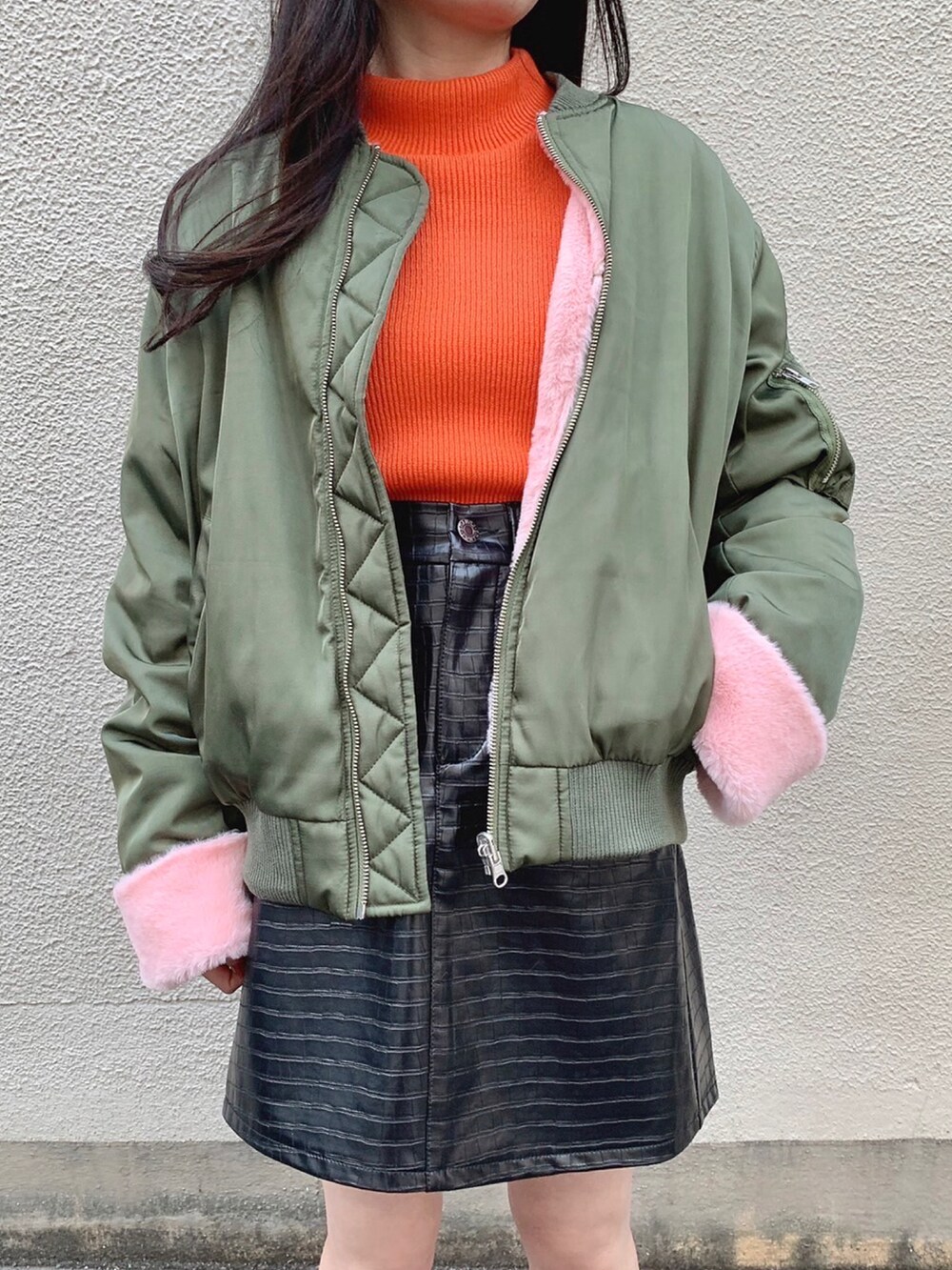 ブラック系のスカート、グリーン系のMA-1、オレンジ系のニット/セーターを着用したレディースの冬コーディネートの2枚目の写真