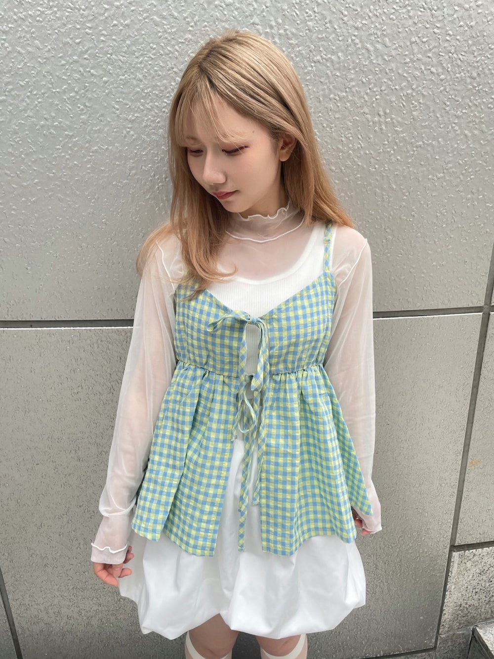 イエロー系のキャミソール、ホワイト系のスカート、ホワイト系のTシャツ/カットソーを着用したレディースの春コーディネートの2枚目の写真