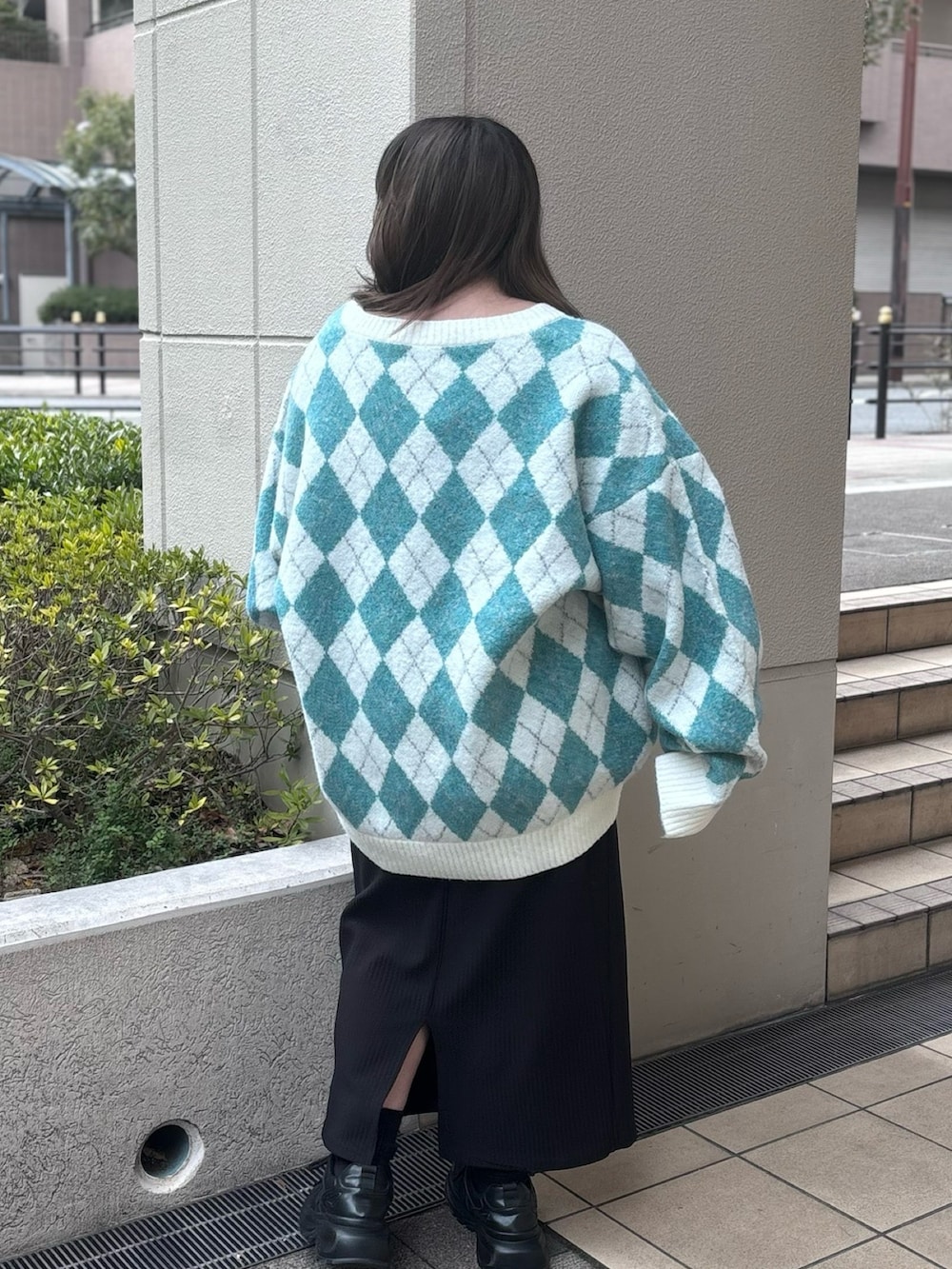 グリーン系のニット/セーター、ブラック系のスカートを着用したレディースの冬コーディネートの3枚目の写真