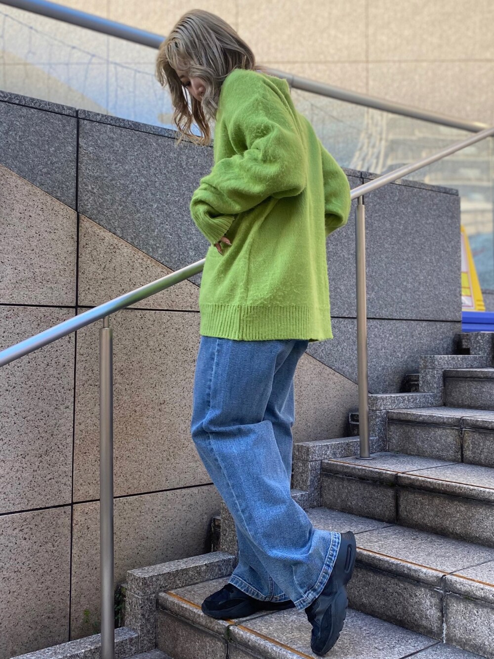 グリーン系のカーディガン/ボレロ、パープル系のTシャツ/カットソー、ブルー系のデニムパンツを着用したレディースの冬コーディネートの2枚目の写真