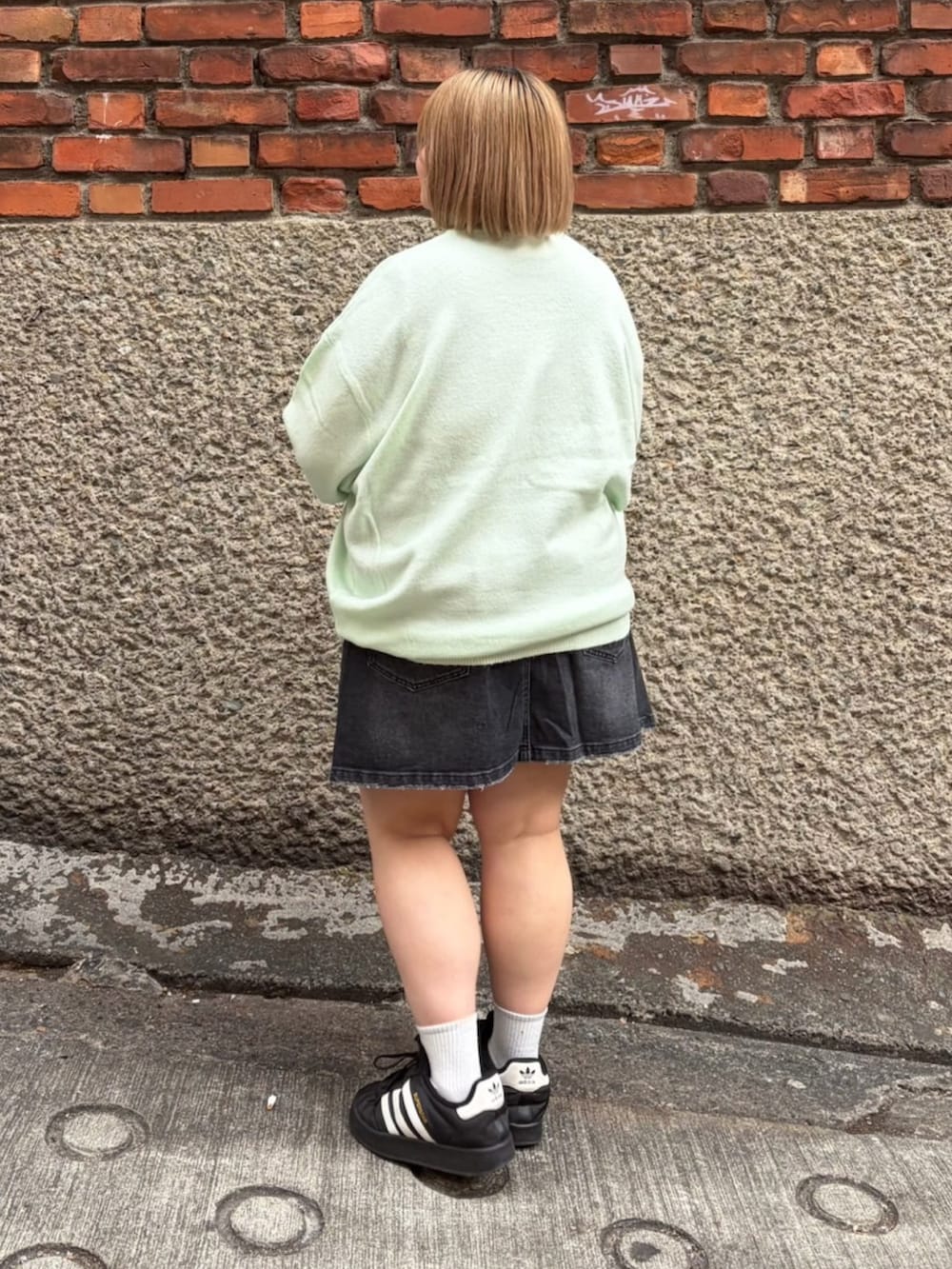 ブラック系のデニムスカート、グリーン系のニット/セーターを着用したレディースの冬コーディネートの3枚目の写真