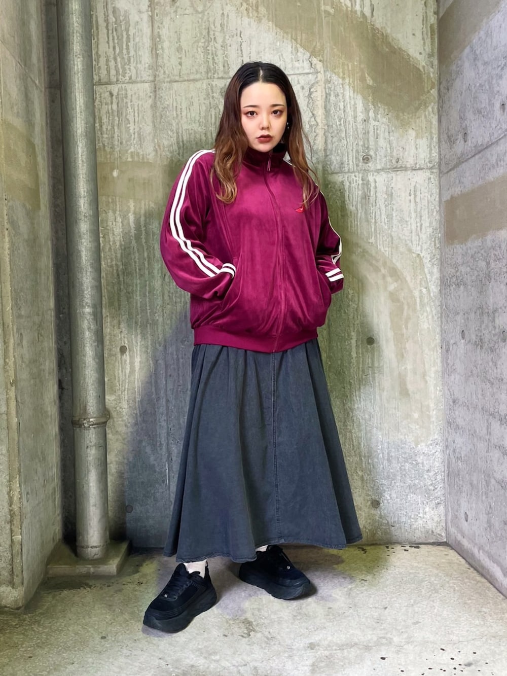 ブラック系のベスト、ブラック系のデニムスカート、レッド系のジャージを着用したレディースの秋コーディネートの2枚目の写真