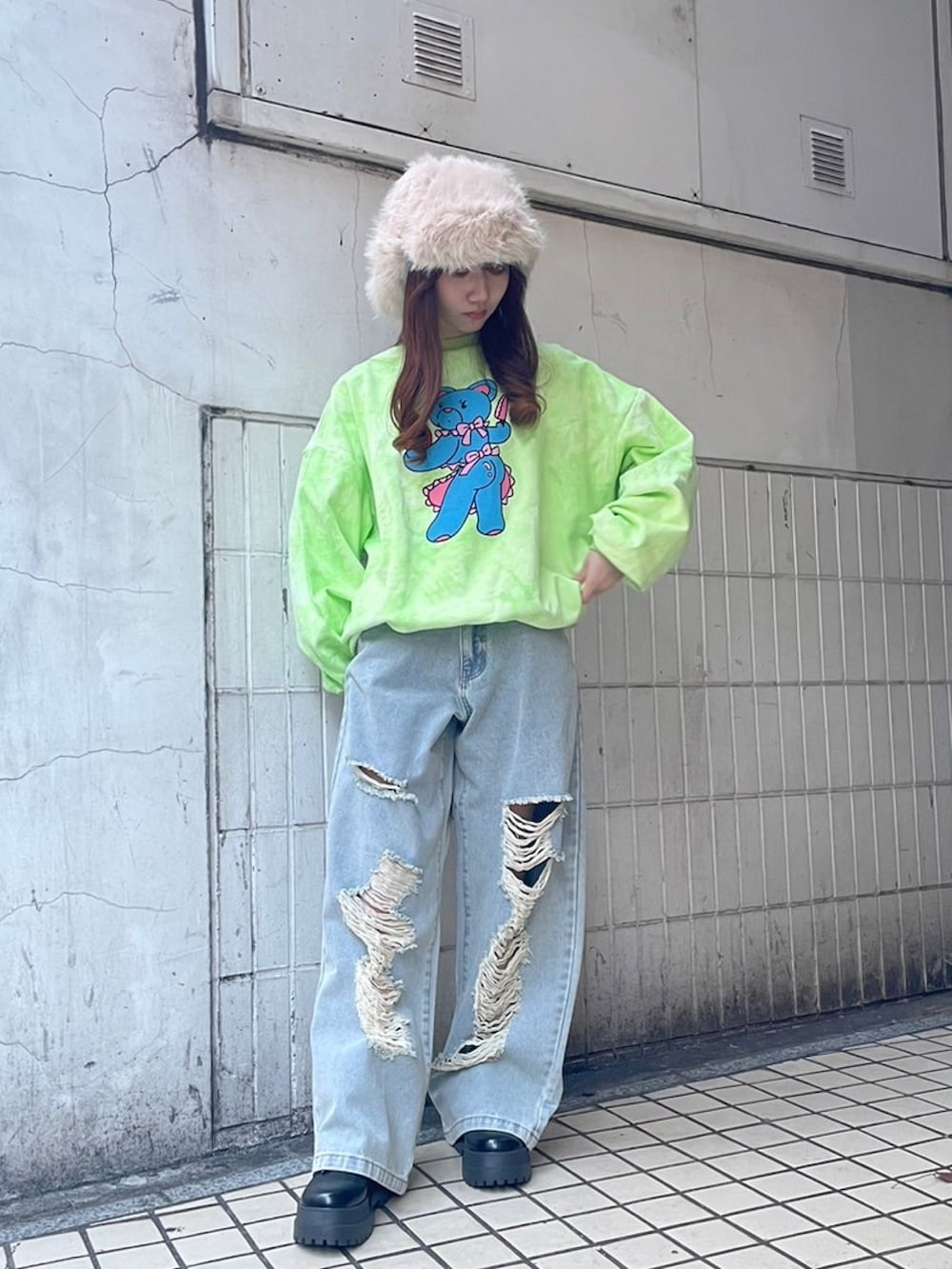 グリーン系のスウェット、ブルー系のデニムパンツ、ホワイト系のキャップを着用したレディースの秋コーディネートの2枚目の写真