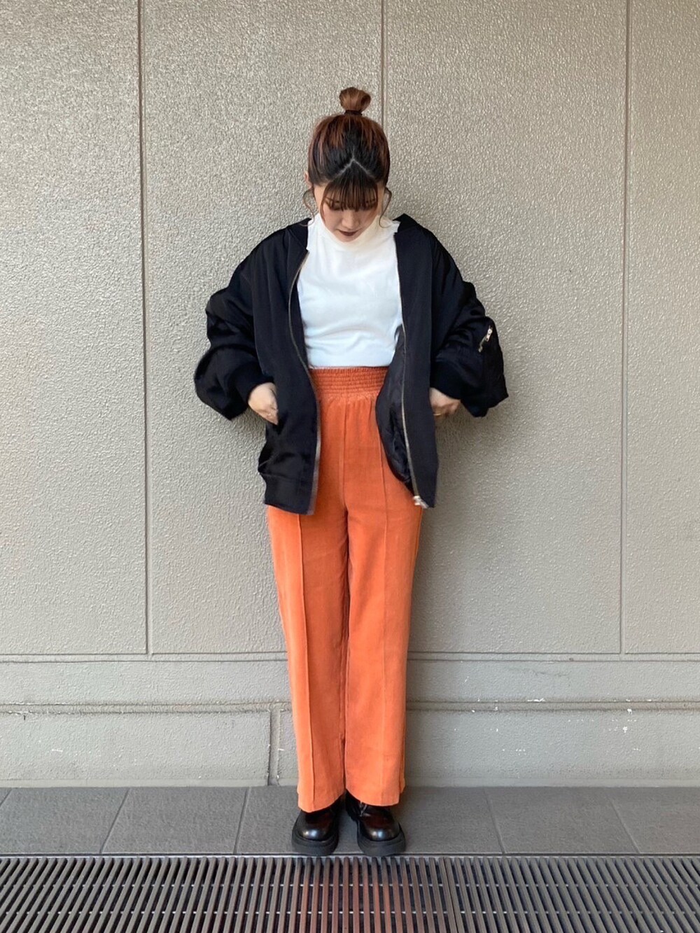 ブラック系のMA-1、オレンジ系のその他パンツ、ホワイト系のTシャツ/カットソーを着用したレディースの秋コーディネートの2枚目の写真