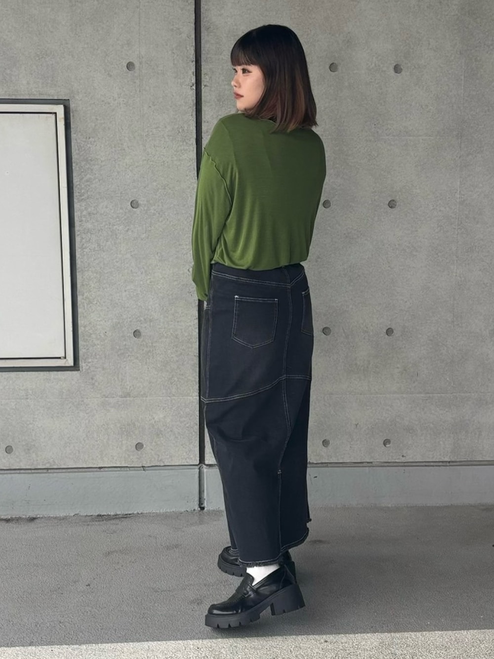 ブラック系のスカート、グリーン系のTシャツ/カットソーを着用したレディースの秋コーディネートの2枚目の写真