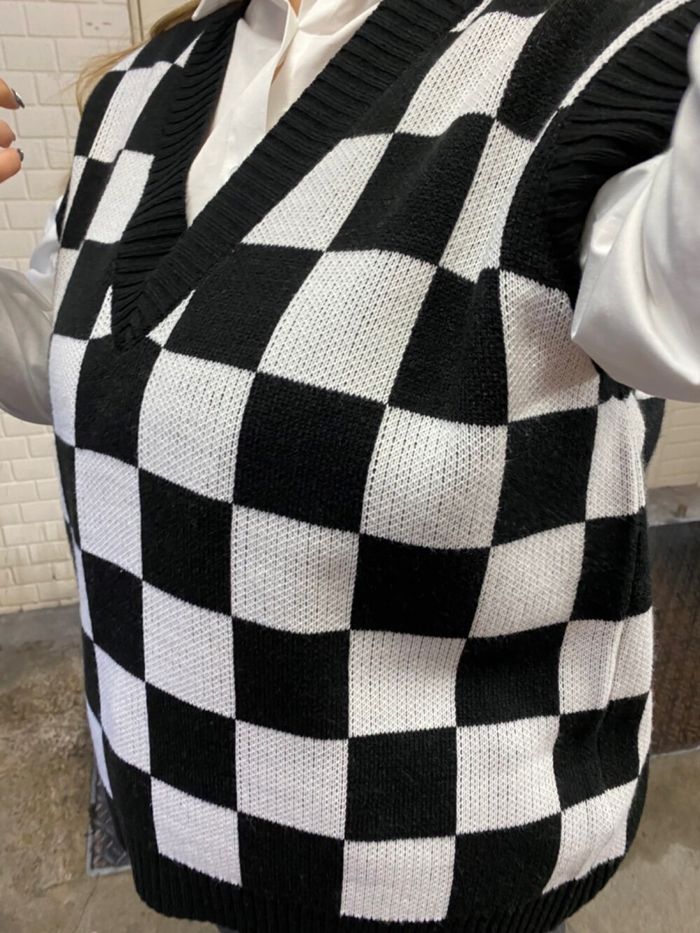 ブラック系のデニムパンツ、ブラック系のローファー、ホワイト系のベストを着用したレディースの春コーディネートの2枚目の写真