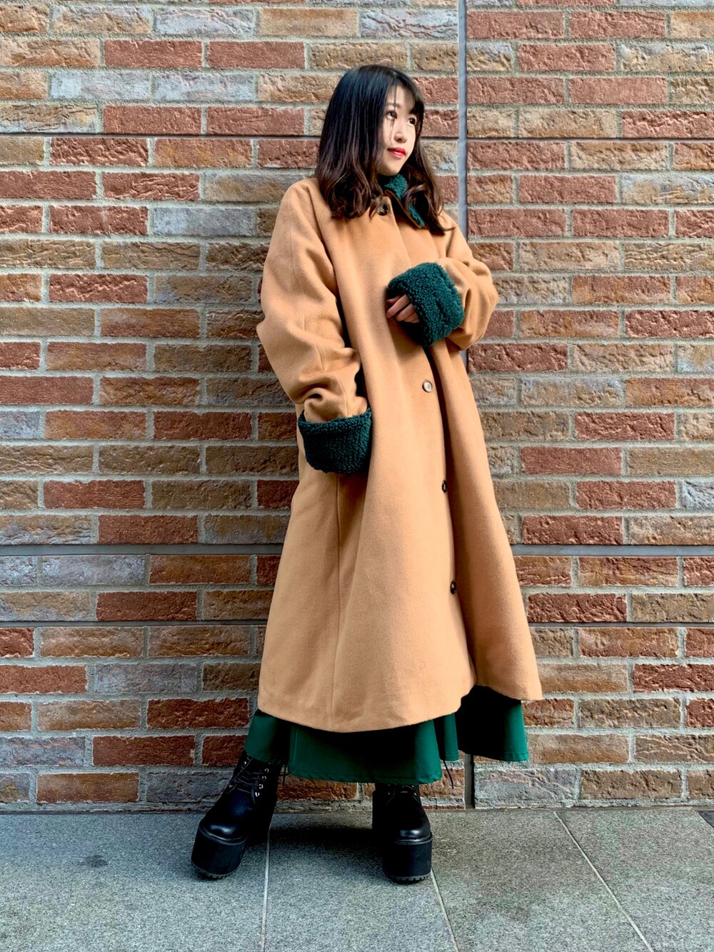 ベージュ系のステンカラーコート、グリーン系のスカート、ホワイト系のニット/セーターを着用したレディースの冬コーディネートの2枚目の写真