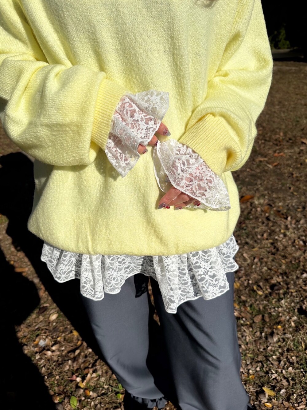 グレー系のスラックス、ホワイト系のTシャツ/カットソー、イエロー系のニット/セーターを着用したレディースの秋コーディネートの3枚目の写真