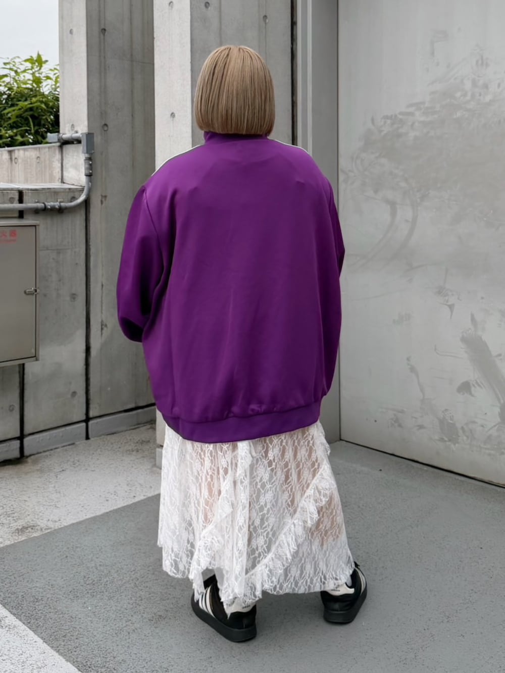 パープル系のジャージ、ホワイト系のスカートを着用したレディースの秋コーディネートの6枚目の写真