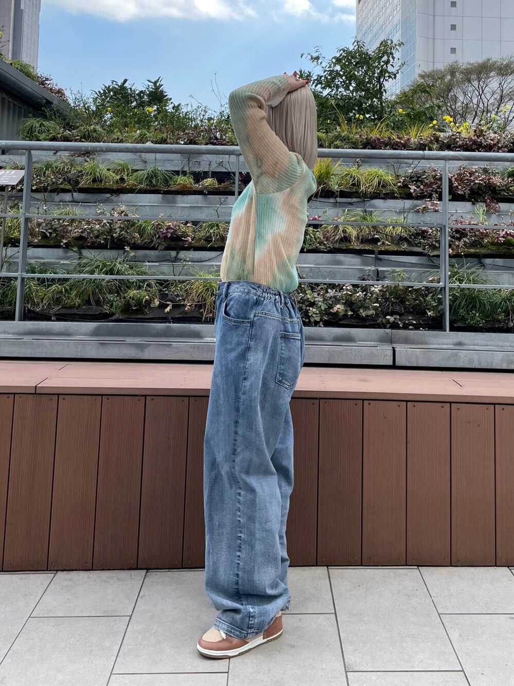 ブルー系のデニムパンツ、グリーン系のニット/セーターを着用したレディースの春コーディネートの2枚目の写真