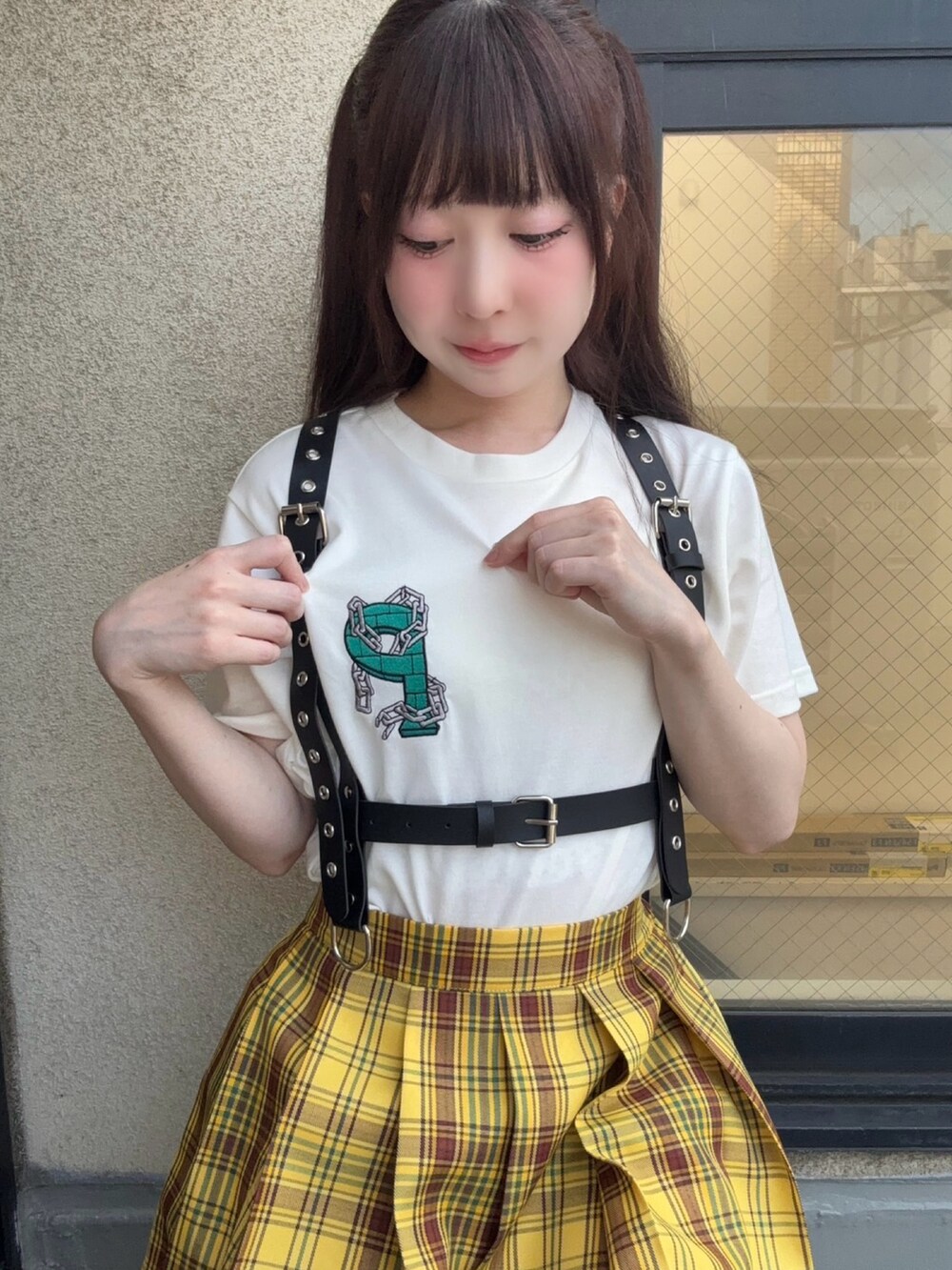 イエロー系のスカート、ホワイト系のTシャツ/カットソー、ブラック系のベルトを着用したレディースの秋コーディネートの2枚目の写真